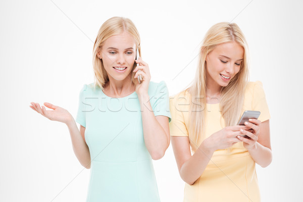 Stock photo: Two cheerful ladies talking at their phones