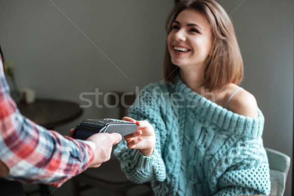 Beautiful young lady pays for her order with debit card. Stock photo © deandrobot