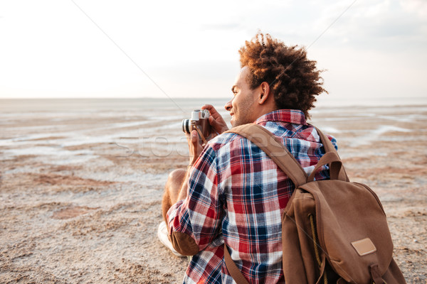 Stock photo: Back view of happy man taking pictures on the beach