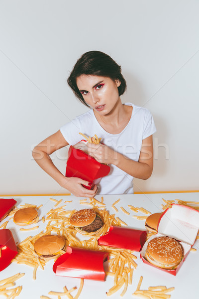 Charming woman sitting and eating french fries from red box Stock photo © deandrobot