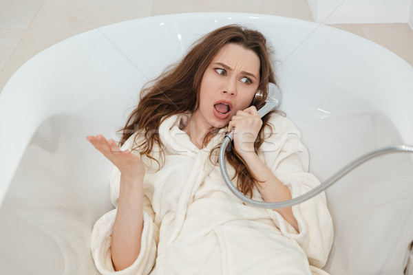 Frowning playful woman imitating phone taking using shower in bathtub Stock photo © deandrobot