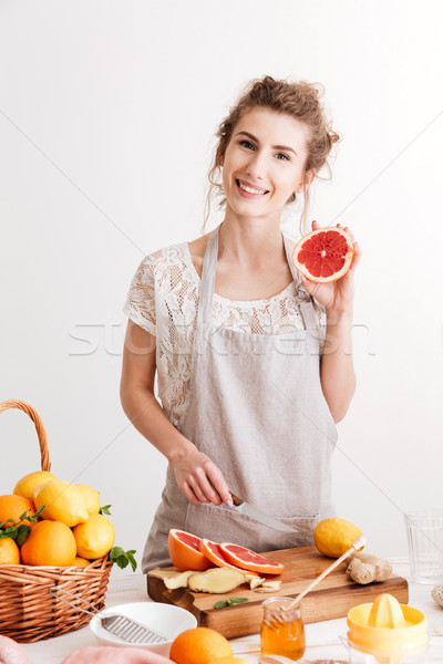 Happy woman standing indoors near table with a lot of citruses Stock photo © deandrobot