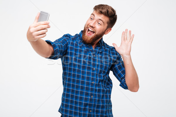 Picture of Happy bearded man in checkered shirt making selfie Stock photo © deandrobot