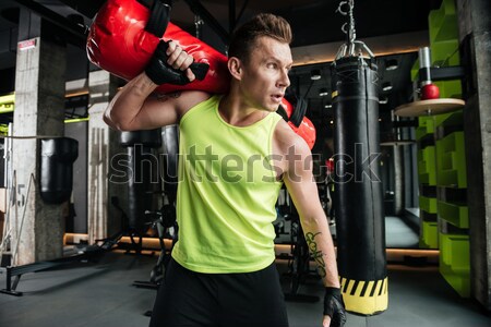 Concentrated sportsman holding weight ball while standing at the gym Stock photo © deandrobot