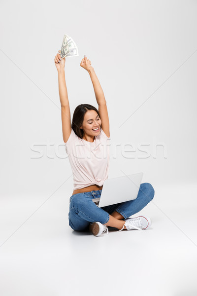 Portrait of a happy cheerful asian girl holding money Stock photo © deandrobot