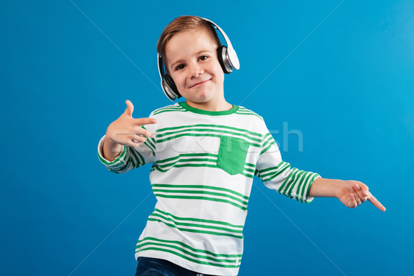 Smiling young boy listening music and dancing Stock photo © deandrobot