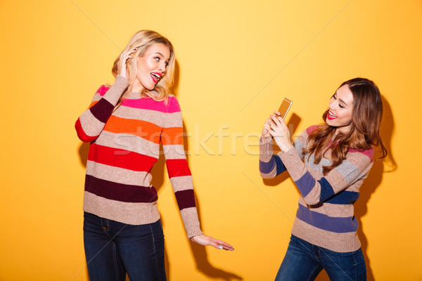 Pretty girl taking a photo of her girlfriend Stock photo © deandrobot