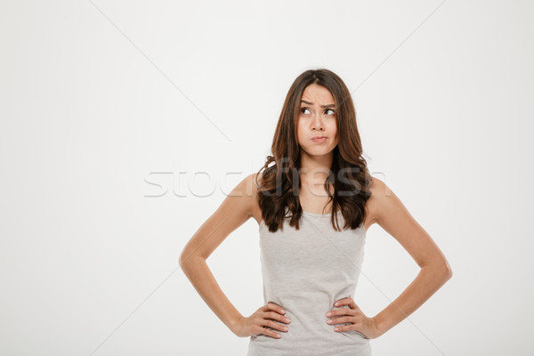 Confused brunette woman with arms on hips looking away Stock photo © deandrobot