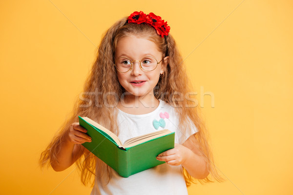 Cute pretty girl wearing glasses looking aside reading book. Stock photo © deandrobot