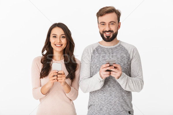 Happy young loving couple chatting by mobile phones Stock photo © deandrobot