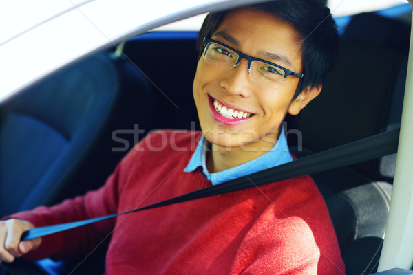 Young asian man fastening seat belt Stock photo © deandrobot