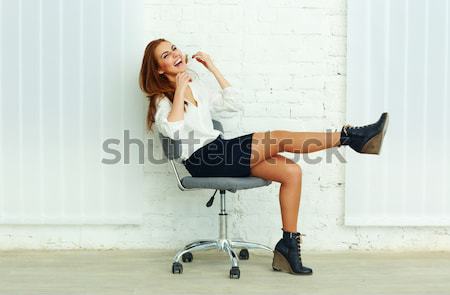 Young cheerful businesswoman sitting on the chair in office Stock photo © deandrobot