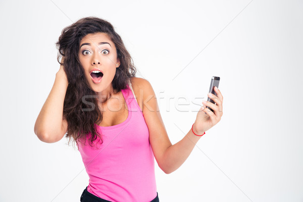 Shocked woman standing with smartphone  Stock photo © deandrobot