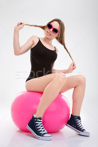 Young sportswoman having fun sitting on pink fitball Stock photo © deandrobot