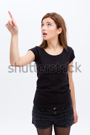 Stock photo: Pensive curious pretty young woman pointing away