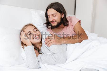 Smiling woman covering her sleeping sister twin with white duvet Stock photo © deandrobot