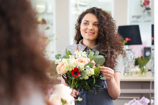 Cheerful woman florist holding flower bouquet and looking at mirror Stock photo © deandrobot