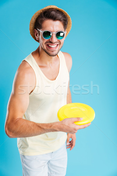 Smiling man in hat and sunglasses playing with frisbee disk Stock photo © deandrobot
