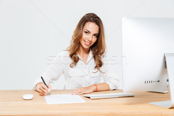 Jovem empresária assinatura documentos sessão mesa de escritório Foto stock © deandrobot
