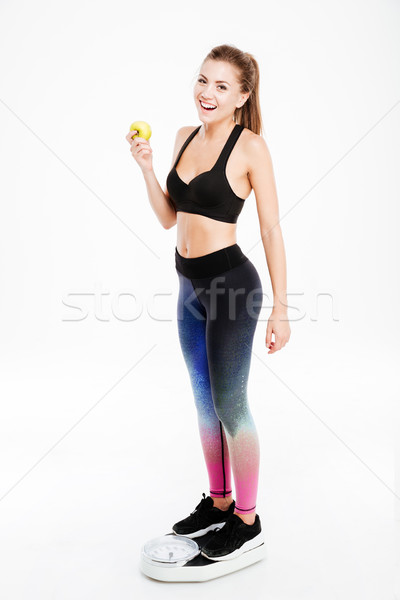 Happy excited young sportswoman standing on weigh scale Stock photo © deandrobot