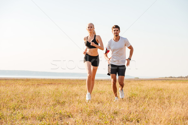 Smiling sports couple running outdoors Stock photo © deandrobot