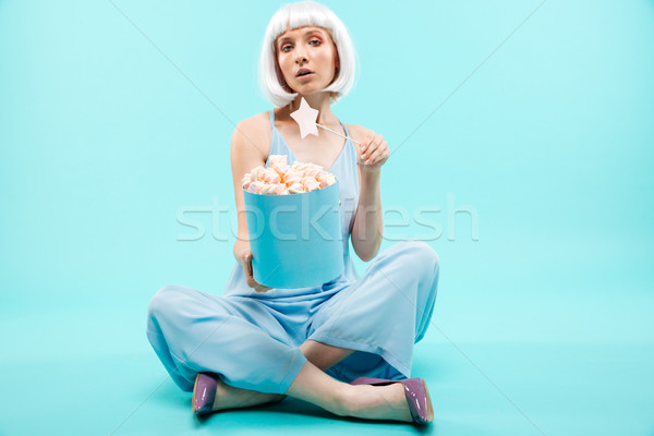 Beautiful young woman with marshmallows sitting and using magic wand Stock photo © deandrobot