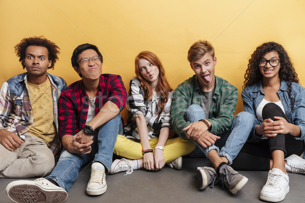 Stock photo: Comical playful young people sitting and making funny faces