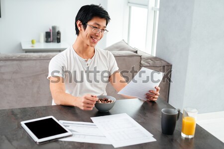 Happy asian man working and eating Stock photo © deandrobot