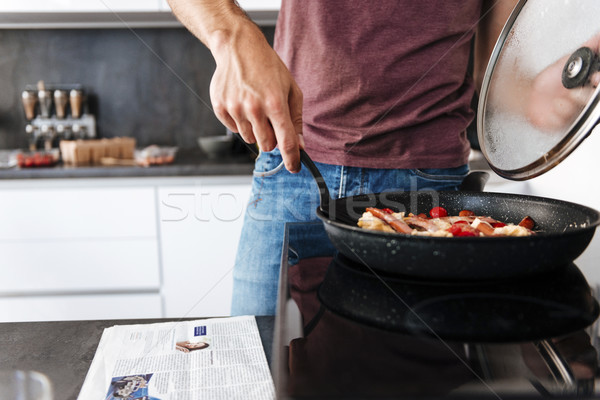 Stock photo: Man standing and using frying pan on the kitchen