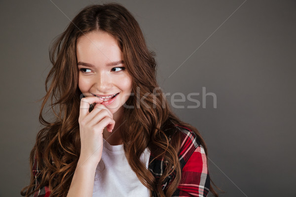 Smiling young woman with long hair standing and looking away Stock photo © deandrobot