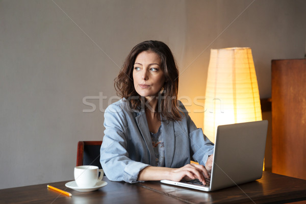 Thinking concentrated woman writer sitting indoors using laptop Stock photo © deandrobot