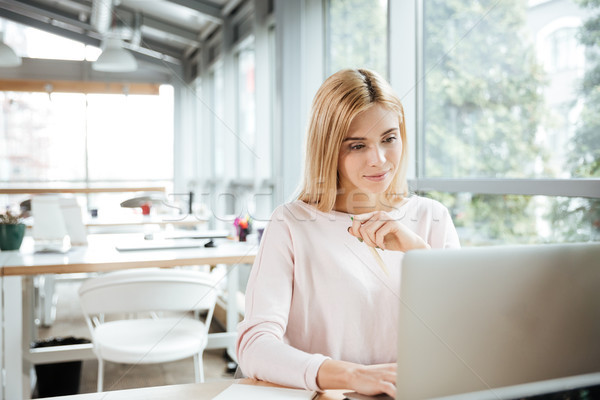 Concentrated lady sitting in office coworking while using laptop Stock photo © deandrobot