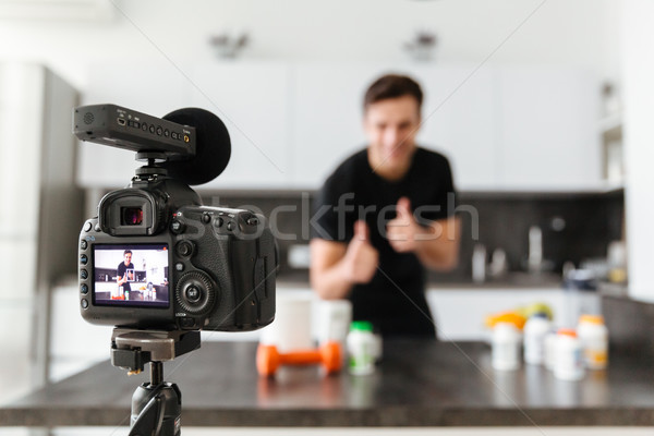 Smiling young man filming his video blog episode Stock photo © deandrobot