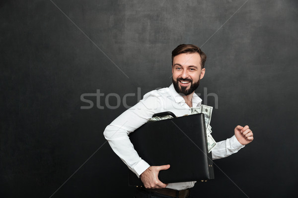 Funny picture of lucky man holding black briefcase full of dolla Stock photo © deandrobot