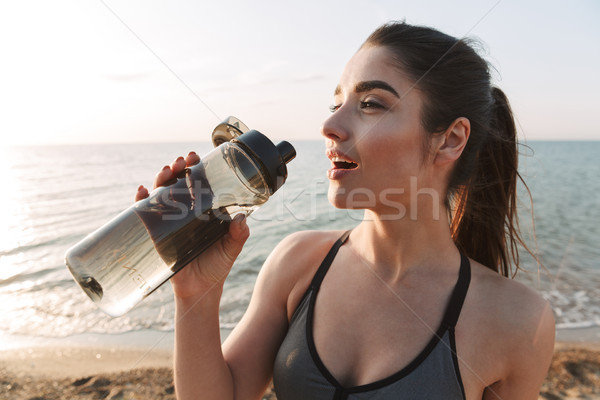 Közelkép szomjas fiatal sportoló ivóvíz üveg Stock fotó © deandrobot