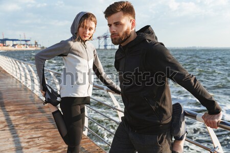 Confident young couple warming up before jogging Stock photo © deandrobot