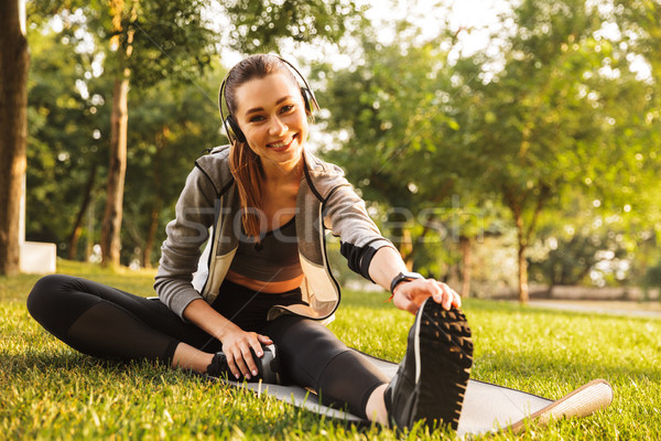 Photo of athletic sportswoman 20s in sportswear listening to mus Stock photo © deandrobot