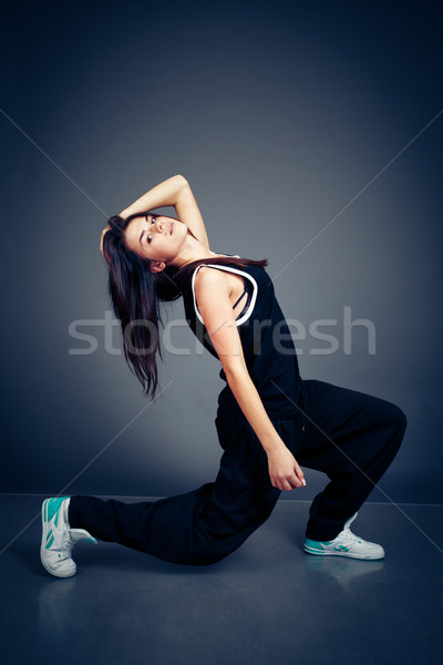 Stock photo: Young beautiful dancing woman in black hip-hop suit on dark background