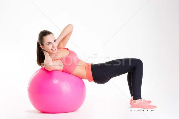 Cheerful beautiful fitness girl training abdominal muscles using fitball  Stock photo © deandrobot