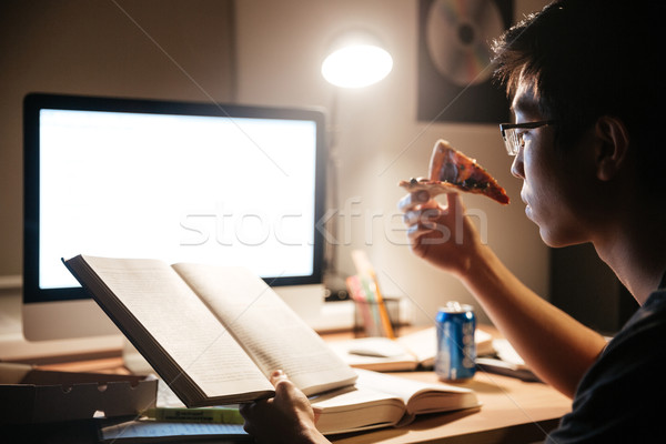 Koncentruje człowiek jedzenie pizza czytania asian Zdjęcia stock © deandrobot