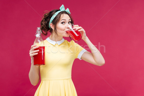 Charming happy pinup girl standing and drinking juice Stock photo © deandrobot
