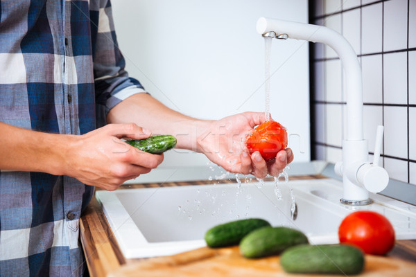 Closeup of man washing tomatoes and cucumbers on the kitchen Stock photo © deandrobot