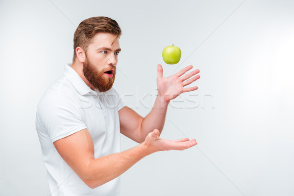 Funny bearded man throwing up a green apple Stock photo © deandrobot