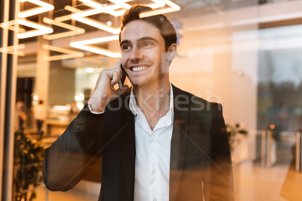 Smiling business man talking on phone behind the glass Stock photo © deandrobot