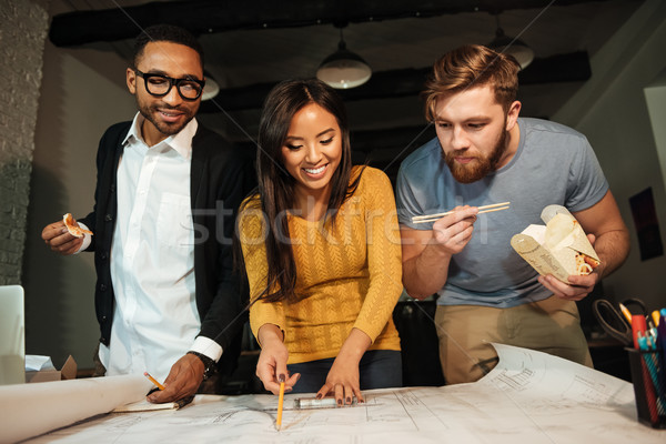 Happy architects working at night while looking on project Stock photo © deandrobot