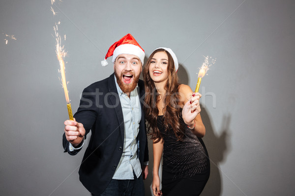 Happy cheerful couple celebrating holding glasses with champagne and petards Stock photo © deandrobot
