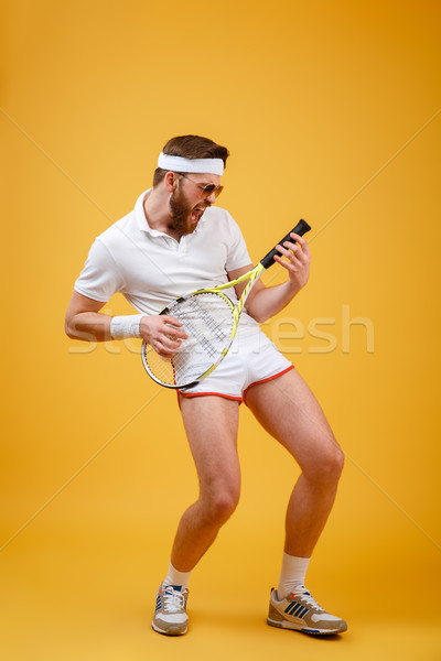 Vertical image of Funny sportsman playing on tennis racquet Stock photo © deandrobot