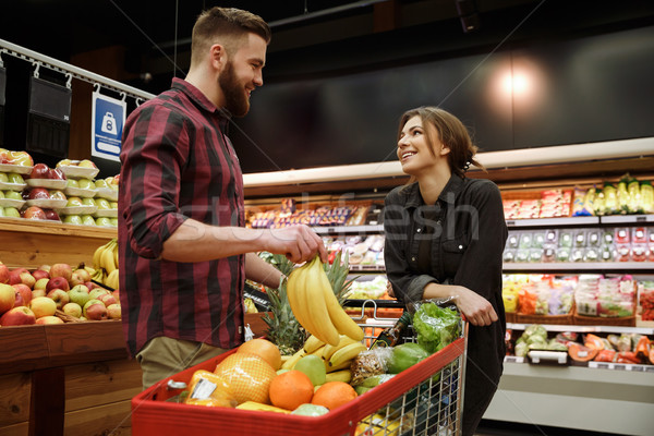 Young loving couple in supermarket with shopping trolley Stock photo © deandrobot