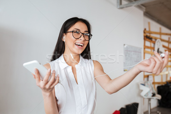 Stock photo: Woman sharing one earphone with somebody for listening to music