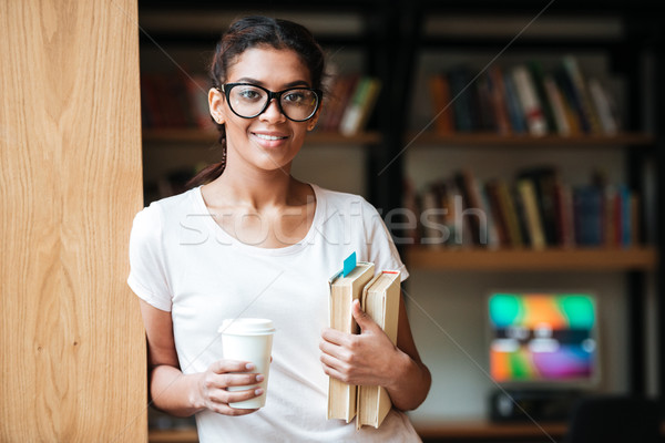 Happy african woman wearing glasses standing in library Stock photo © deandrobot